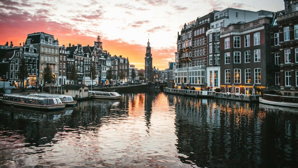 Zonsondergang boven de grachten in Amsterdam met rondvaartboten en historische gebouwen sfeer van Amsterdam met kinderen.