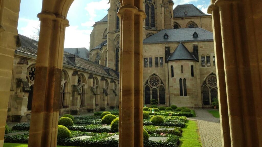 Kloostertuin met bogen en kerkgebouw in Trier met verzorgde tuin en historische architectuur