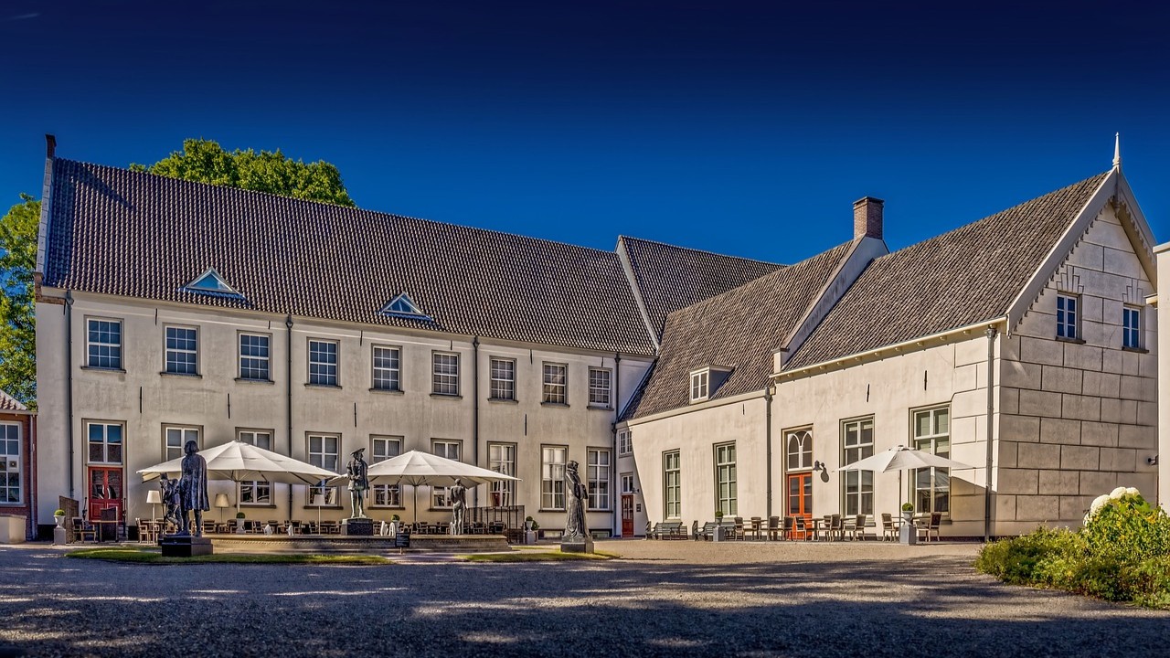 Terras met parasols en beelden bij een historisch landgoed, sfeervolle plek waar bekende Nederlanders graag tafelen